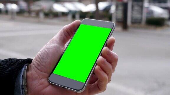 一名男子手持绿屏智能手机