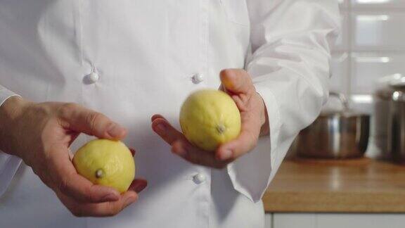 特写镜头:男炊具在厨房里摆弄一个柠檬-慢动作