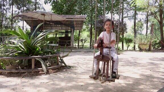 快乐的亚洲小女孩喜欢在户外公园的操场上骑马和荡秋千