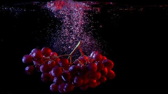 红葡萄掉进水里溅起水花的慢动作镜头