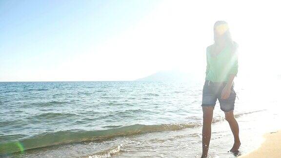 美丽的女孩赤脚走在海边