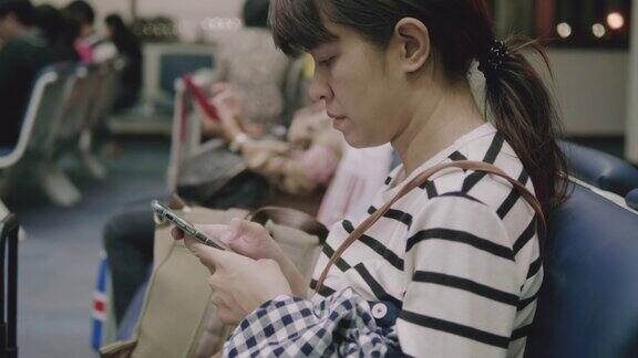 一个亚洲女人在机场打智能手机