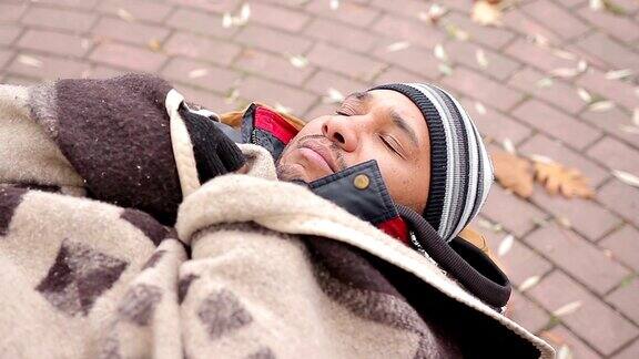 一张可怜的无家可归者的脸他睡在长凳上感到寒冷和不高兴