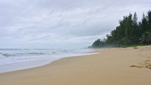 热带海洋和泡沫海浪拍打着海滩和阴天
