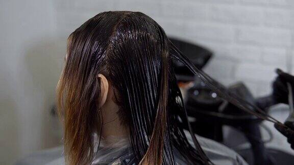 美容院里发型师给一位年轻女子做头发