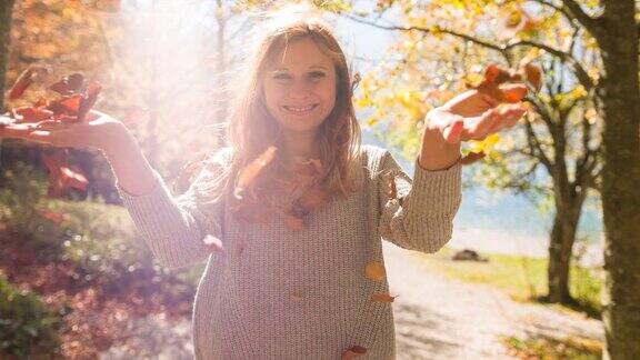 快乐的女人在湖边抛五颜六色的秋叶