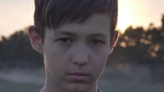 一个悲伤的男孩在麦田里的肖像在日落看近镜头