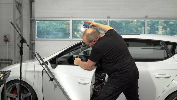 一名专业的汽车修理工正在用热风枪加热车门在没有使用工具油漆的情况下修复凹痕用PDR法修复车门凹痕的过程