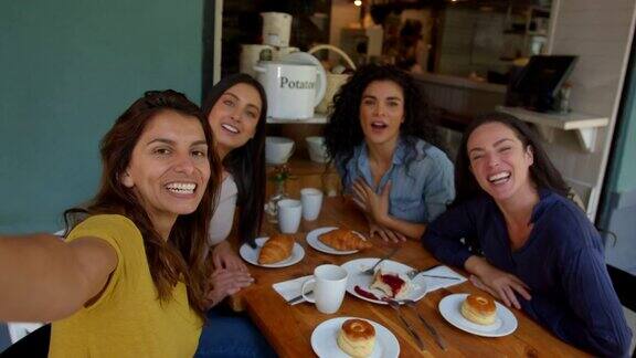 一群女性朋友在咖啡店聊天微笑着向镜头挥手致意