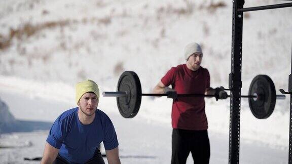 在冬天年轻的健美运动员举着沉重的杠铃