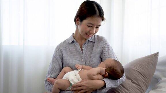 4k一个2个月大的亚洲新生儿躺在妈妈的肩膀上睡觉妈妈抱着她哄她入睡爱和温暖在卧室里