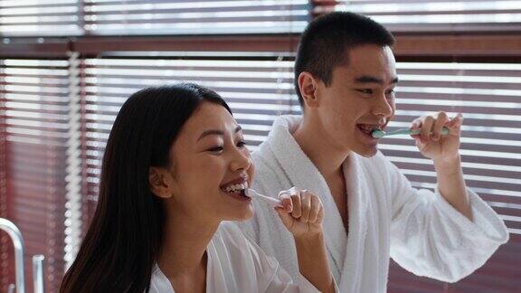 快乐的日本夫妇在现代浴室用牙刷刷牙