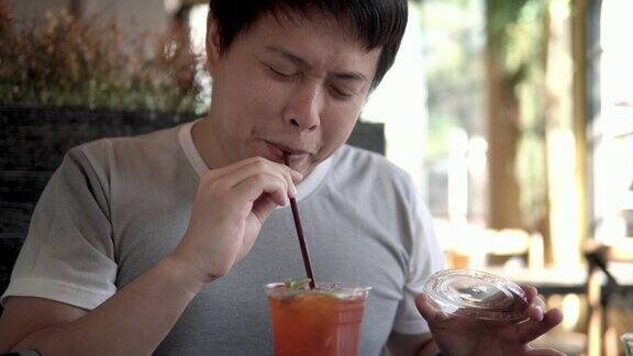 亚洲男子吃柠檬茶时做鬼脸