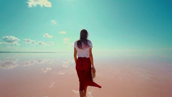后视图女人在粉红色的盐湖享受美丽的自然