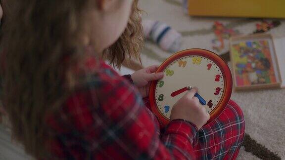 儿童早期发展小女孩在家里用钟表玩具学习时间