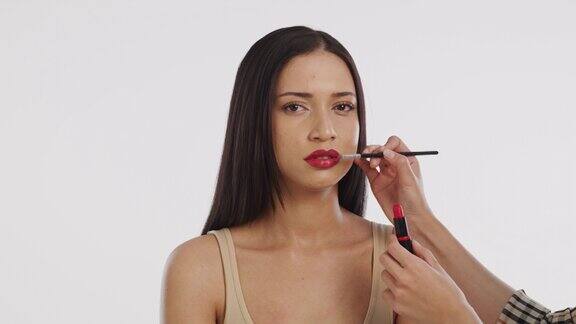 一个美丽的年轻女子在白色背景下化妆的4k视频片段