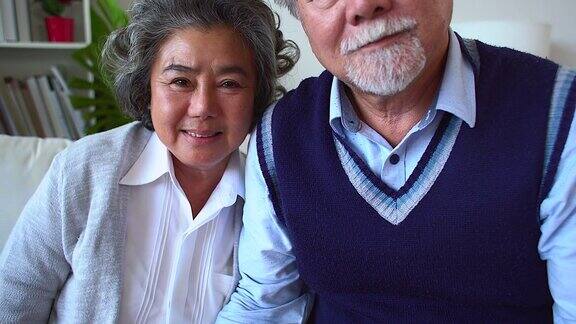 快乐的亚洲老年夫妇享受生活一对浪漫的老年夫妇坐在家里的沙发上大笑