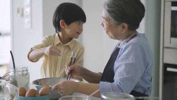 亚洲华人奶奶在厨房教孙子烘焙