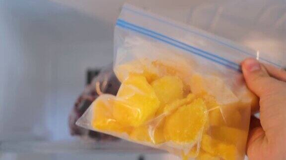 女人的手从冰箱里拿了一袋冰冻芒果