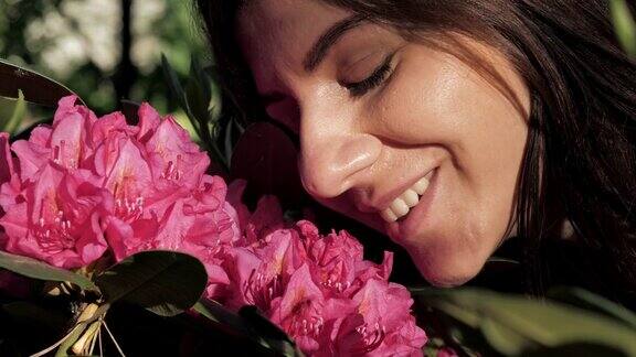 女人嗅粉红色盛开的花特写