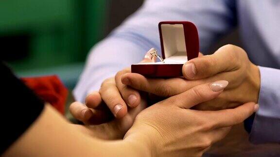 男人打开装有钻石订婚戒指的盒子女人摸着他的手求婚