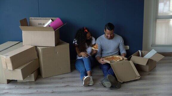 幸福的夫妇搬进了他们的新公寓吃着披萨休息一下