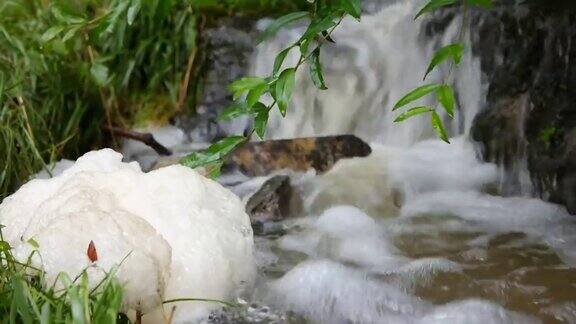 大雨后在瀑布底部的小森林溪流表面形成的大的脏浮渣泡沫球阴天实时没有人