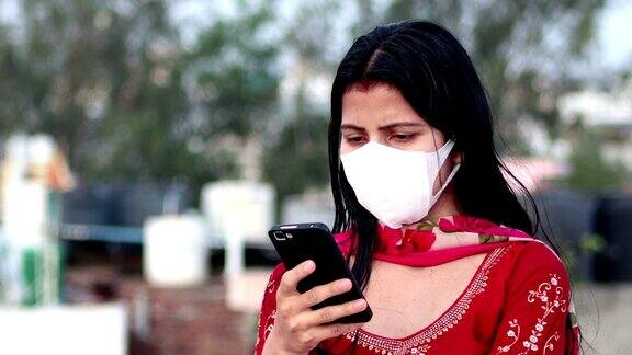 印度妇女用污染口罩遮脸以预防COVID-19并使用手机
