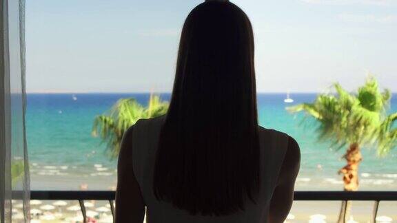 女士打开阳台滑动玻璃门从阳台上欣赏地中海海景
