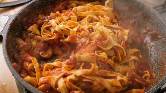 慢动作搅拌和烹饪意大利扁面配上番茄酱、橄榄和蘑菇