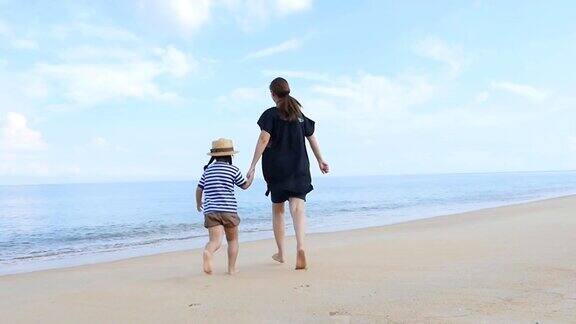 快乐亚洲母亲和女儿一起在沙滩上跑步的慢镜头
