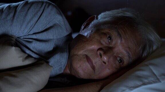 一个沮丧的老人躺在床上无法入睡