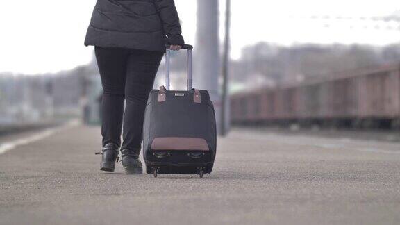 女人提着箱子走在秋天的火车站里后视镜特写