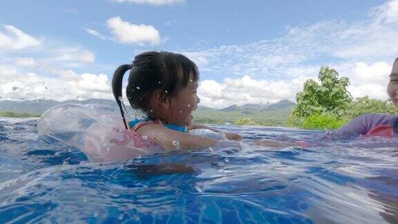 亚洲兄弟姐妹在一个炎热的夏天和家人在游泳池里玩度假的家庭生活方式