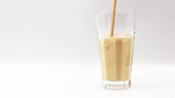 将咖啡味牛奶倒入白色背景的玻璃杯中