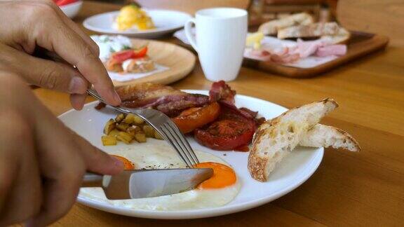 男性双手用刀叉切早餐吃煎蛋配液体蛋黄