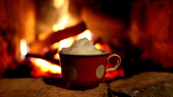 杯子里的雪在壁炉边融化