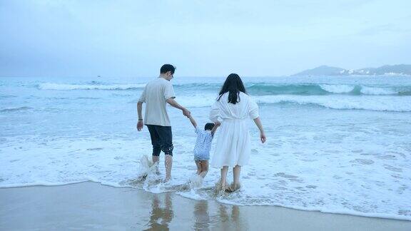 亚洲父亲母亲和儿子走到海边的海滩上