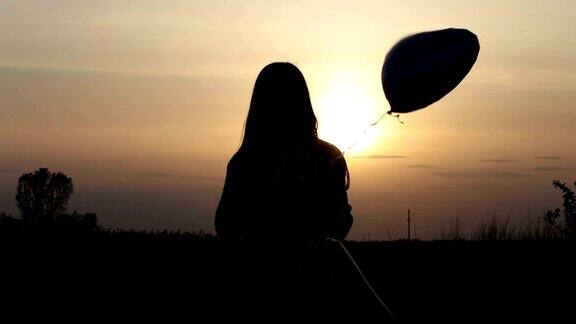 日落时带着心形气球的漂亮女人
