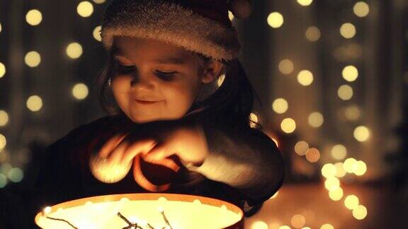 小女孩打开了一个发光的礼物盒发现里面有一个圣诞装饰品