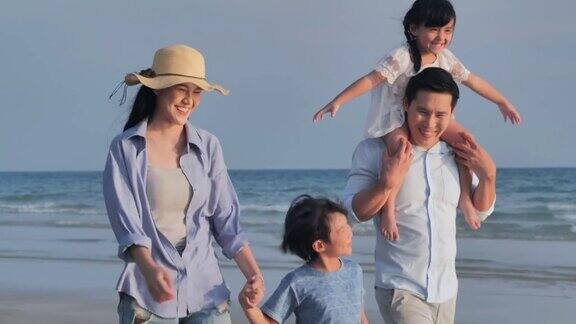 幸福的一家人在海滩上散步快乐的一家人在海滩上享受暑假假期iStock