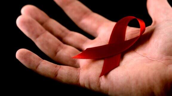 艾滋病红丝带标志落在一个男人的手上