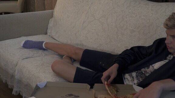 年轻人躺在沙发上吃披萨