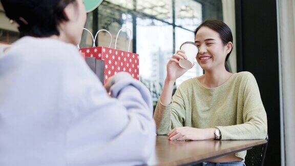 两个女人快乐的亚洲人聊天微笑坐在商店里喝咖啡商场里有这么多购物袋