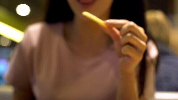 年轻女性在快餐店吃不健康的薯条