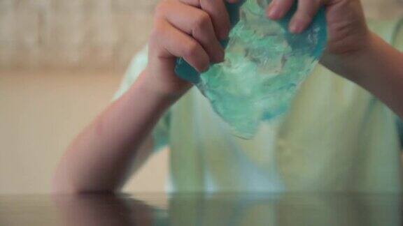 儿童手玩黏液的特写镜头蓝色透明黏液时尚玩具给孩子减压
