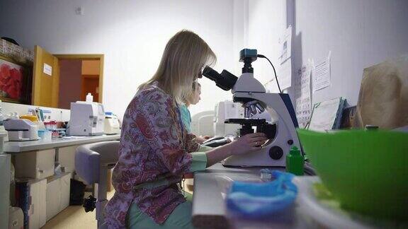 两个年轻漂亮的女人在兽医实验室工作用显微镜观察标本