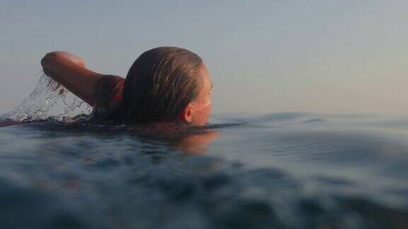 一个十几岁的女孩在暑假日落时在海里游泳