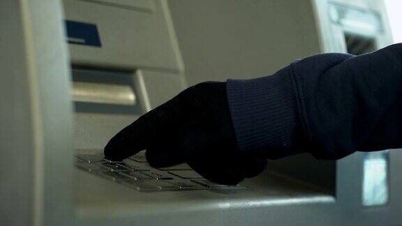戴着手套的可疑男子插入密码从银行账户偷钱