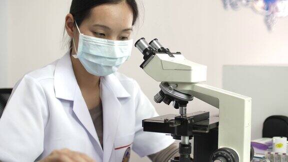 在实验室里用显微镜和药片工作的科学家